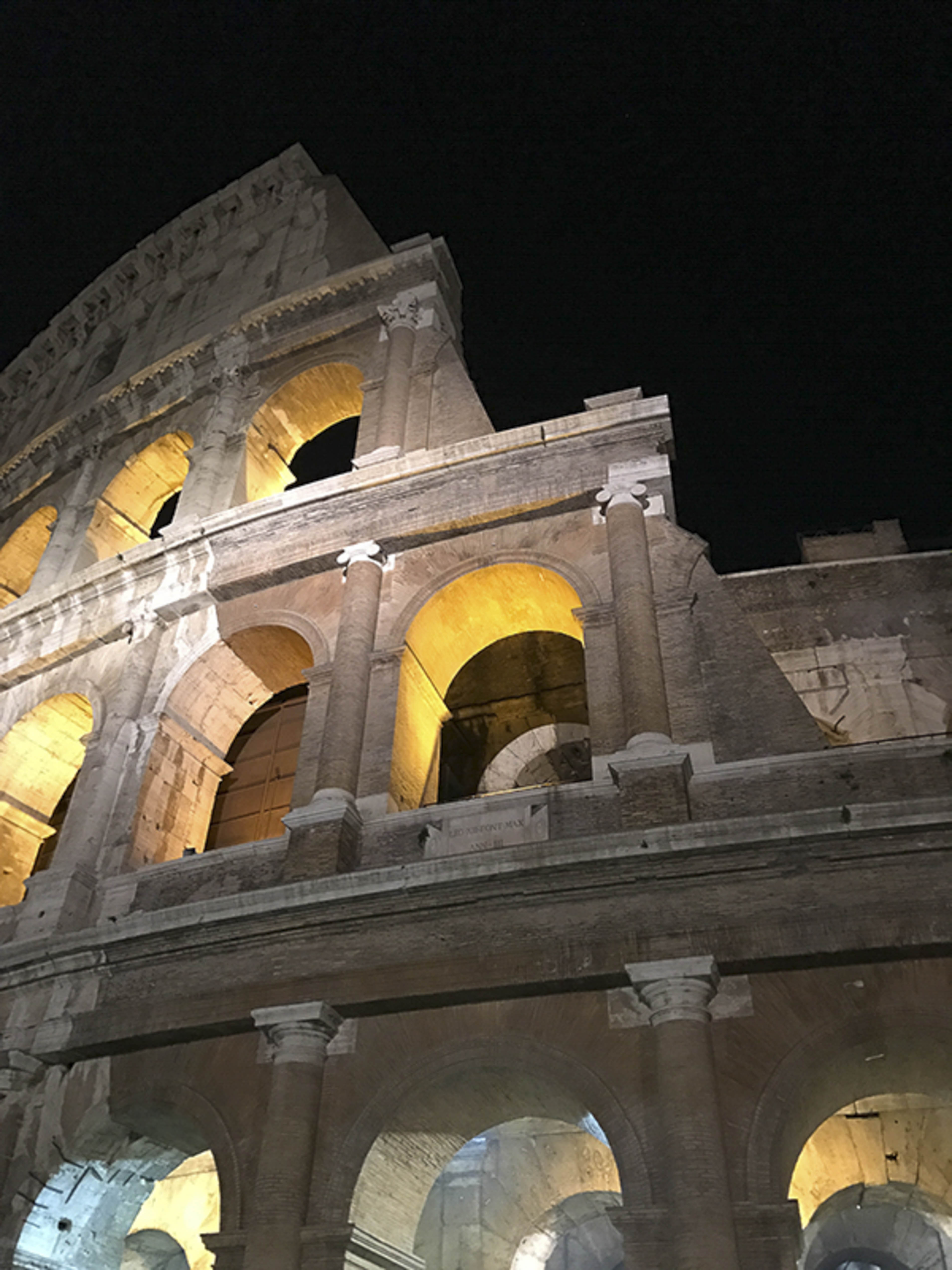 Colosseum arches glowing gold at night, close-up