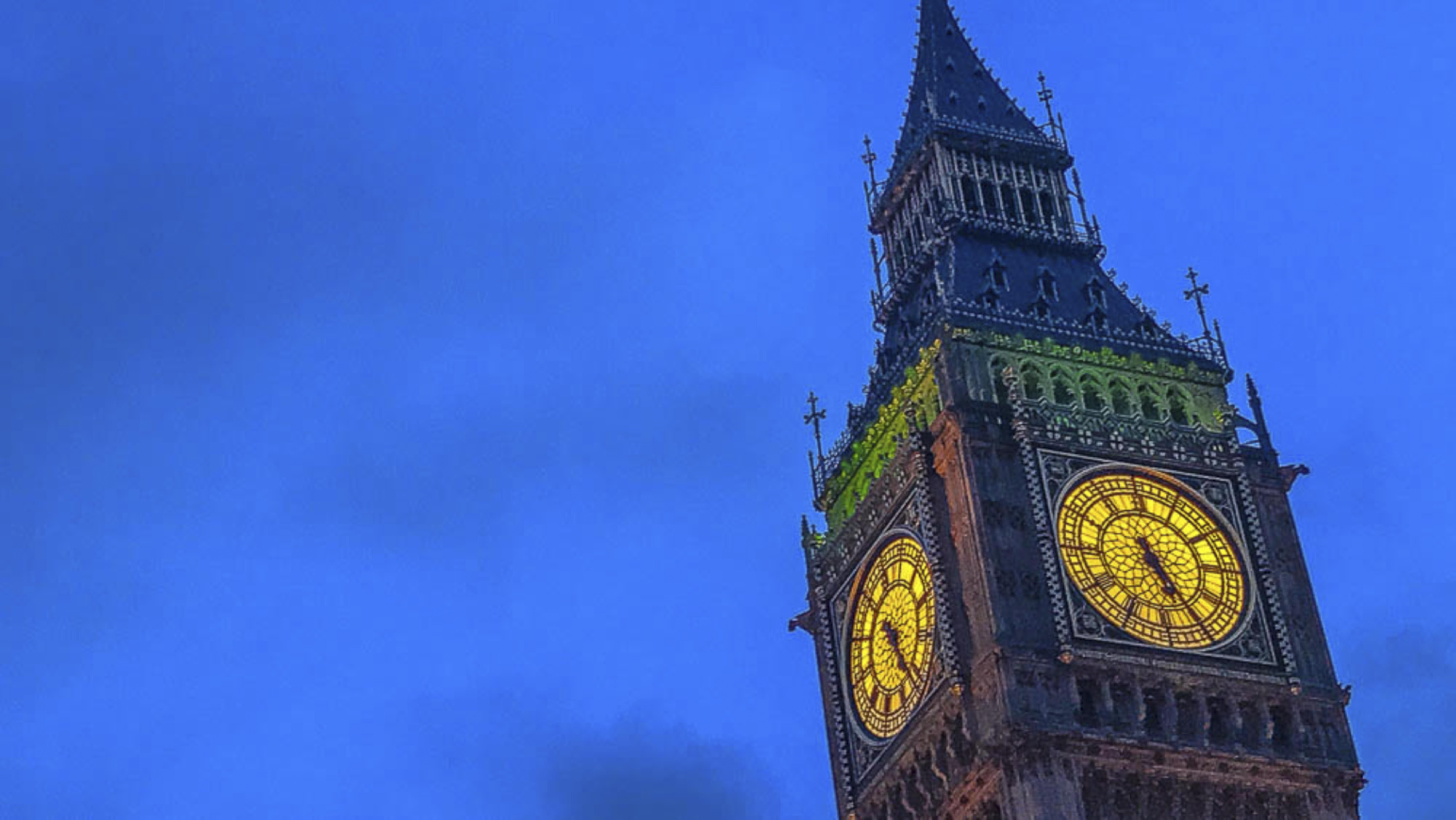Big Ben clock tower at dusk, glowing gold against the deep blue sky