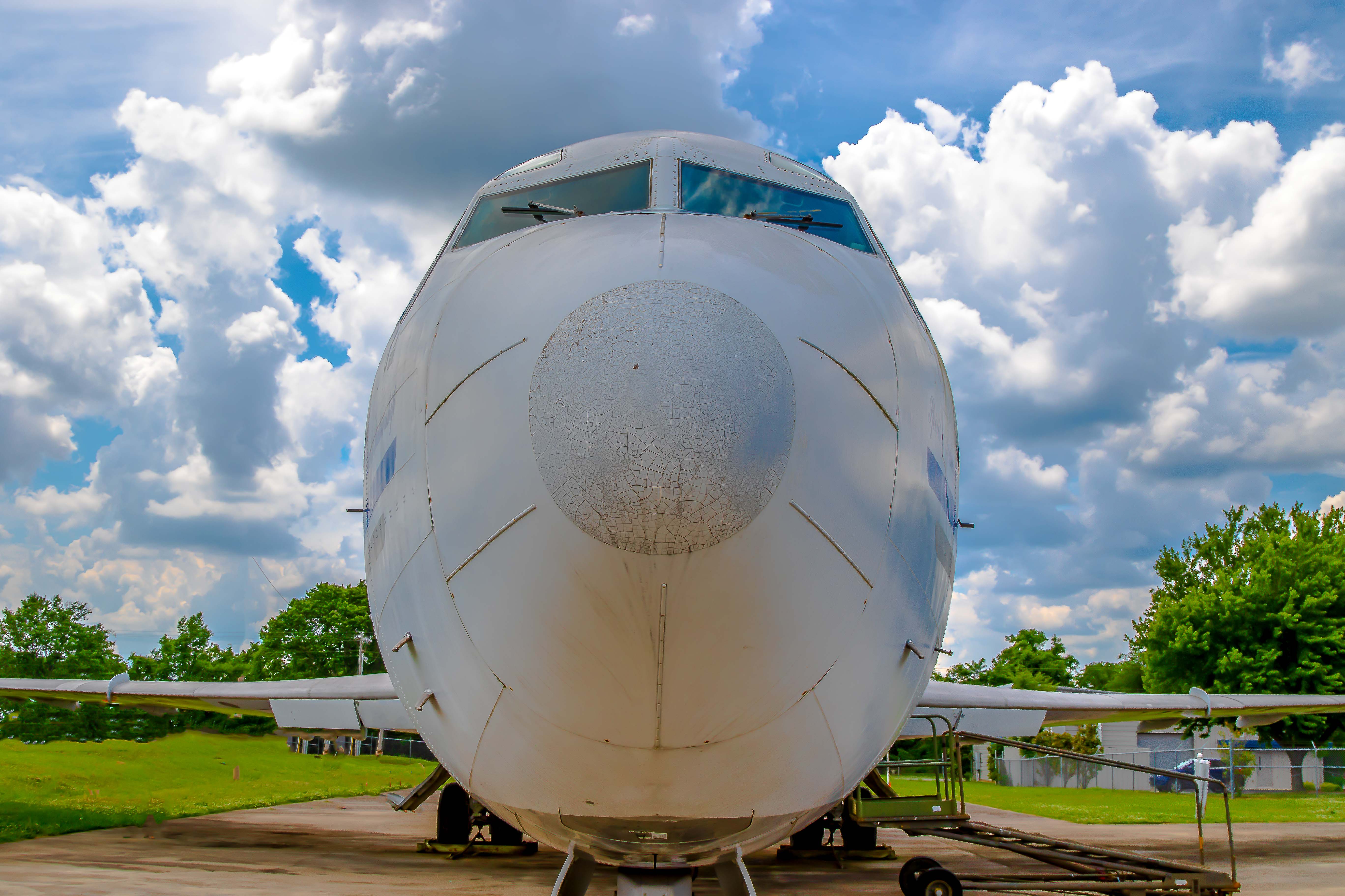 Commercial jet nose-on — blunt fuselage filling the frame against a cloudy sky