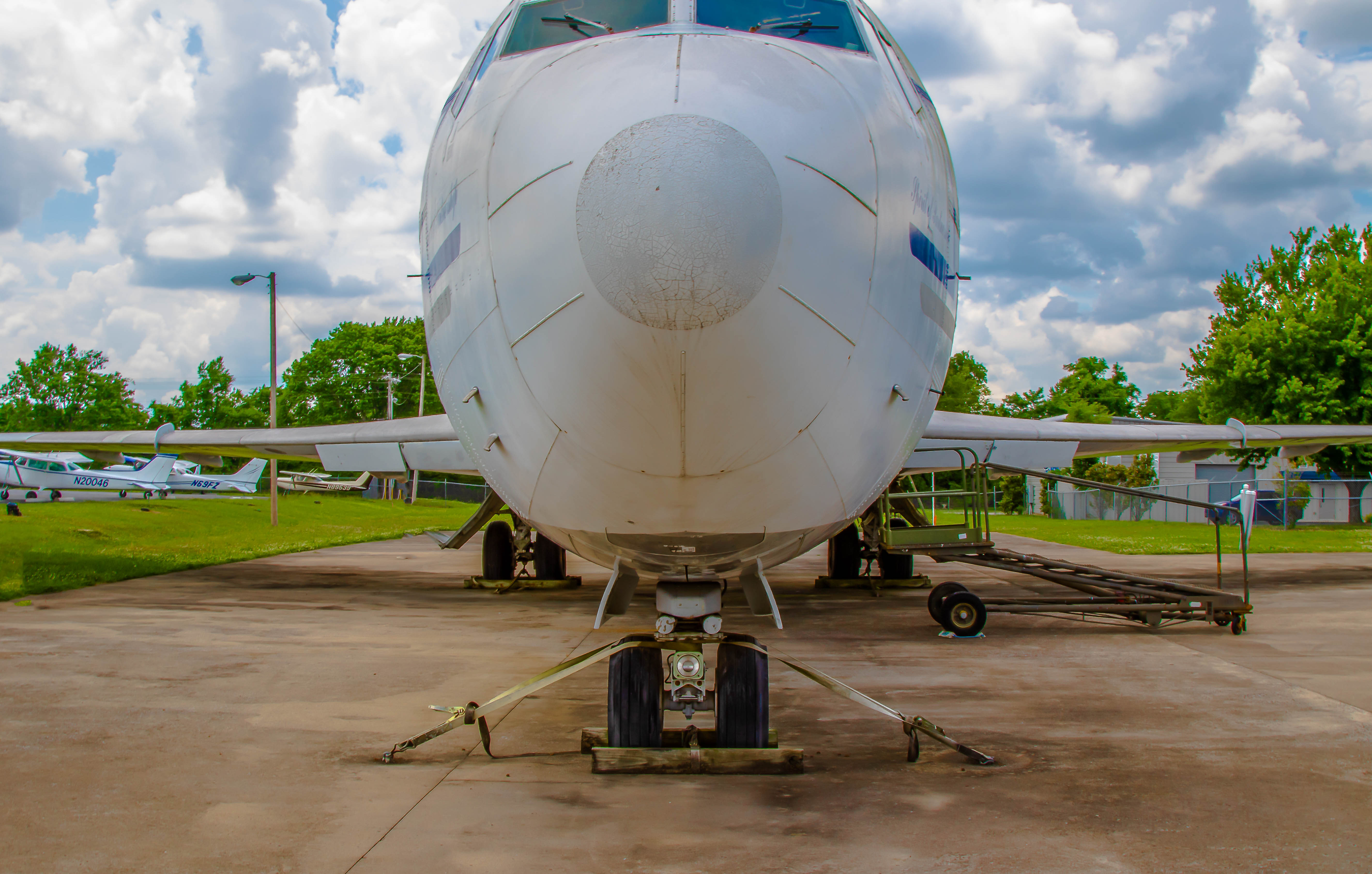 Nose and belly of a commercial jet from the front, other aircraft visible behind