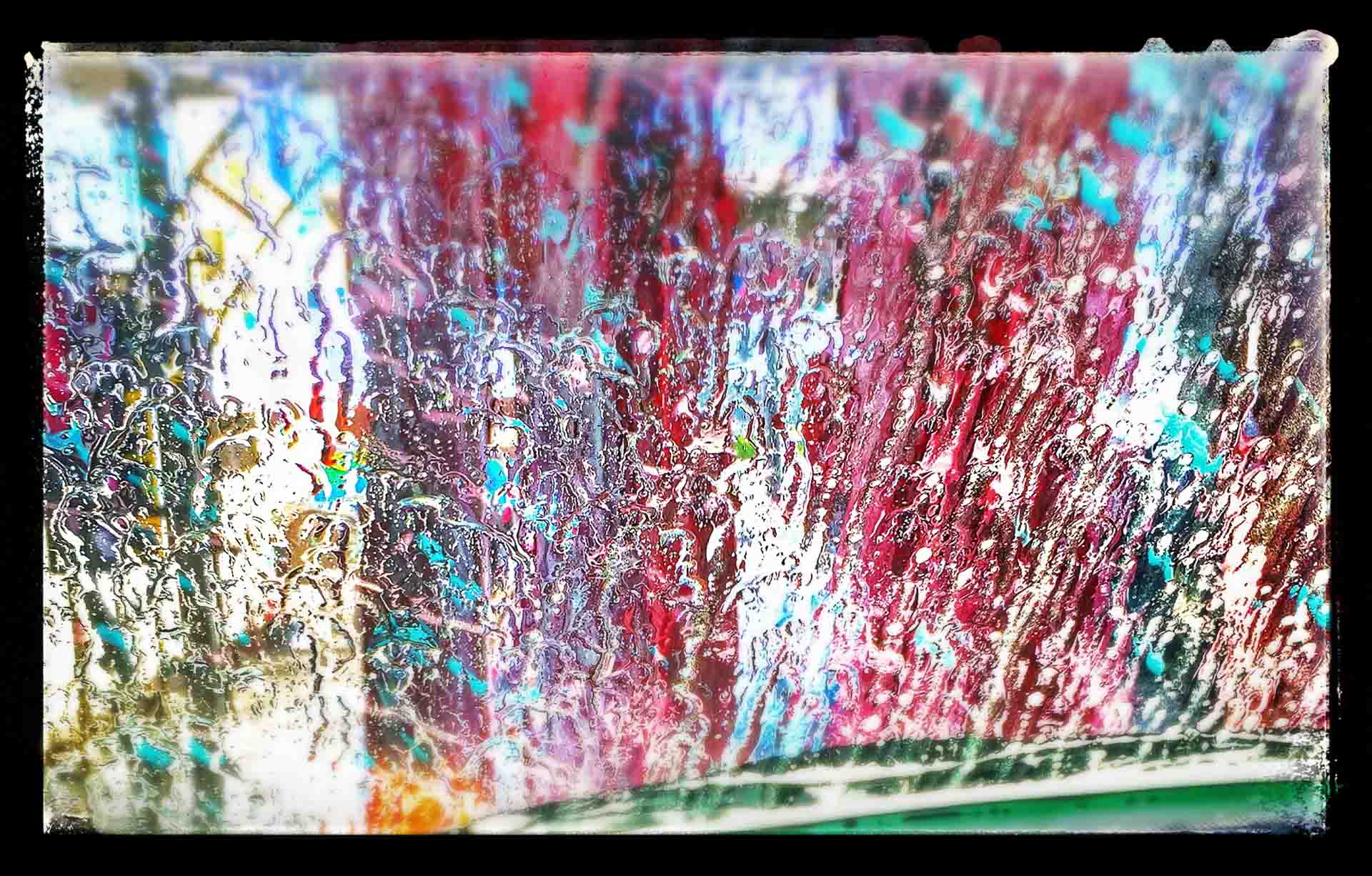 Carwash abstract — spinning brushes through the windshield become a vivid wash of color