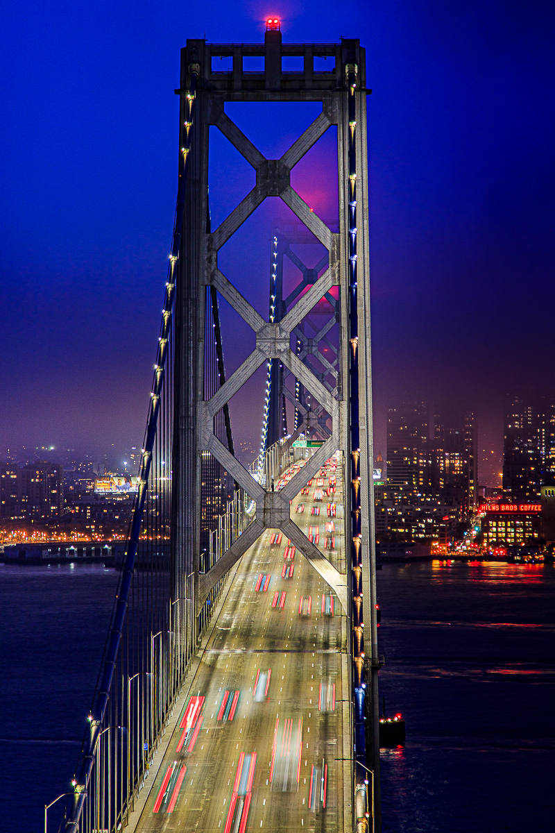 Bay Bridge night reflection — warm lights shimmering on the dark water below