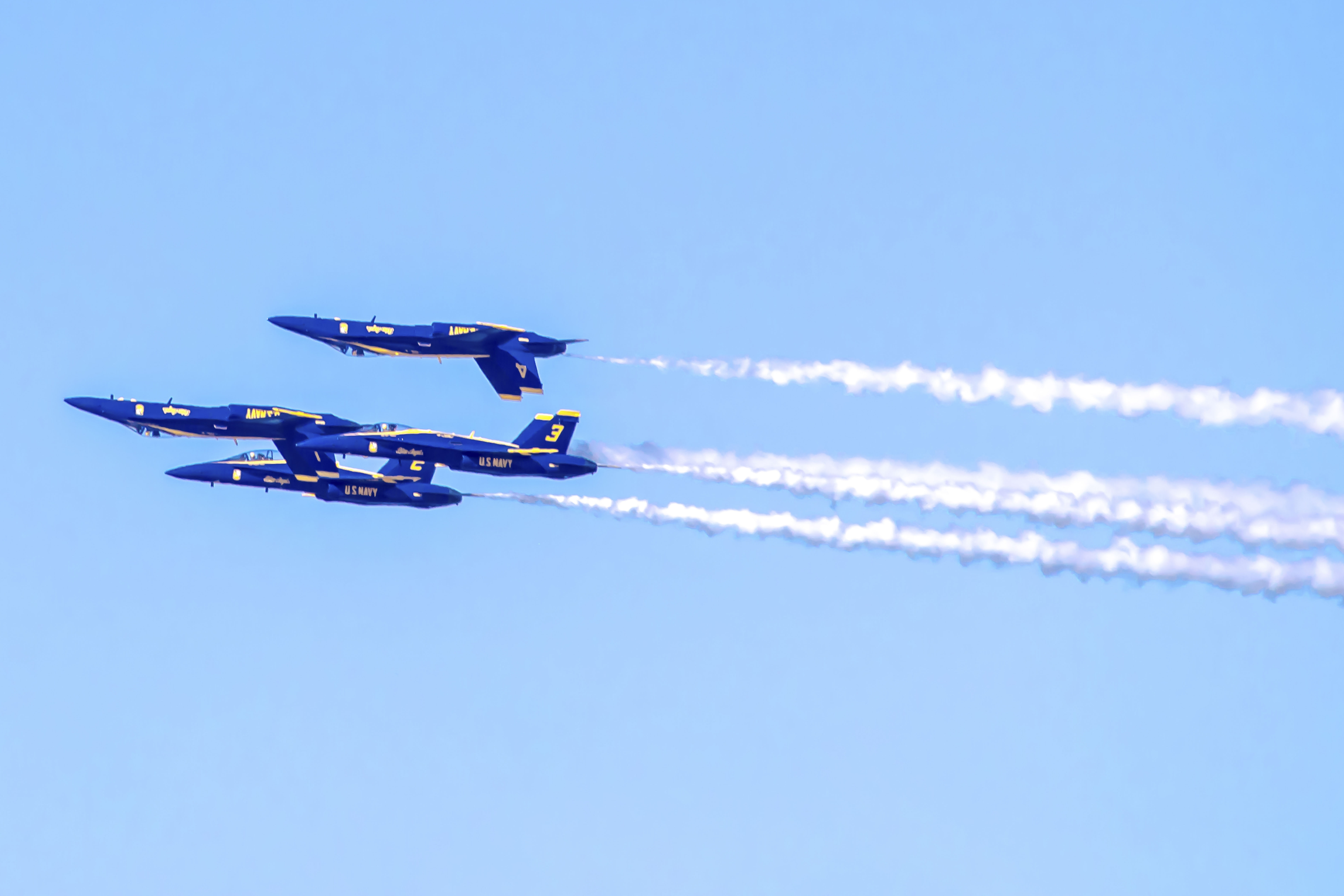Blue Angel turning hard over the Bay, yellow and blue livery crisp against the sky