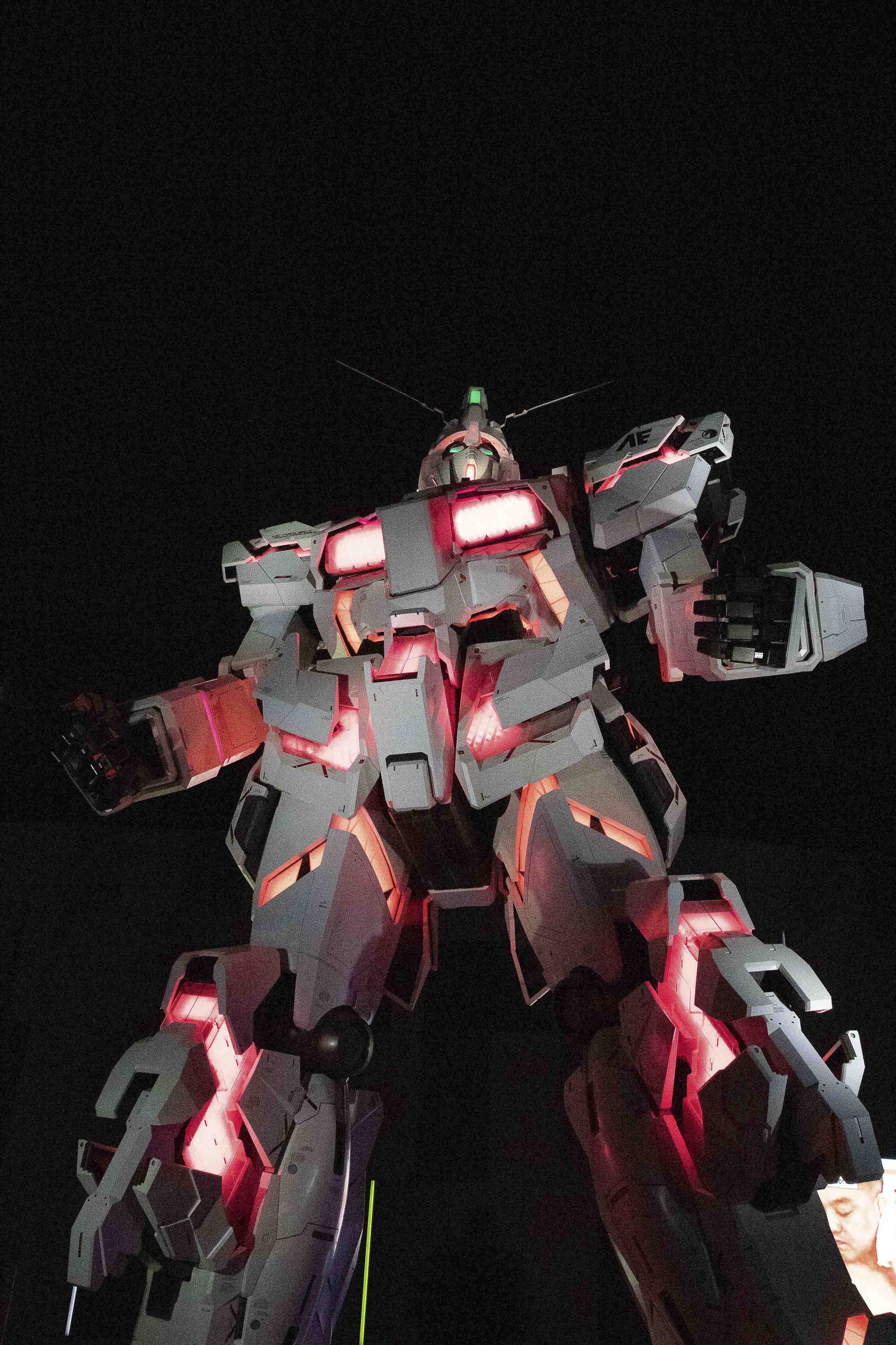 Unicorn Gundam looking skyward, lit in red and white