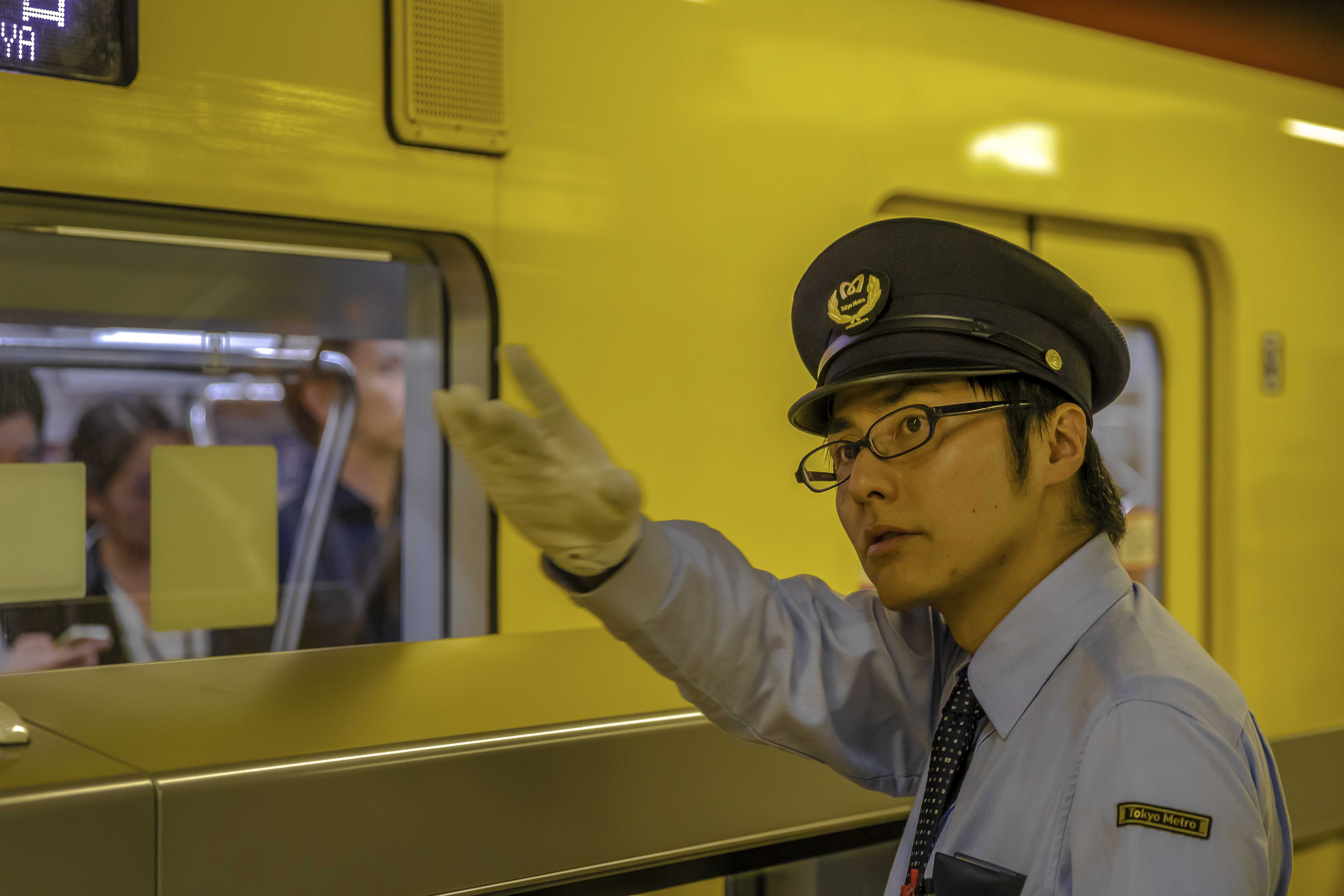 Tokyo train conductor signaling departure on the platform